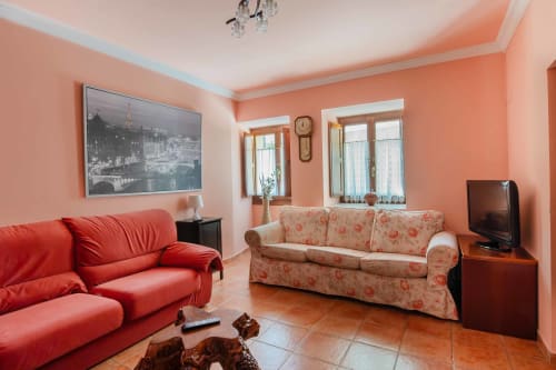 Bright living room at La Viña apartment in Cuzcurrita de Río Tirón with coral walls, red sofa, patterned couch, and mountain