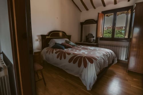 Bedroom with wooden bed, brown patterned bedding, en-suite mirror and dresser at Casas Rurales La Viña rural apartment