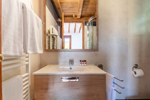Modern bathroom in Casas Rurales La Viña with white sink, wooden vanity, large mirror, and cream tiles