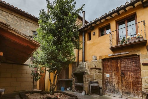 Rustic Spanish courtyard with stone fireplace, wooden doors, and ivy at Casas Rurales La Viña, Cuzcurrita