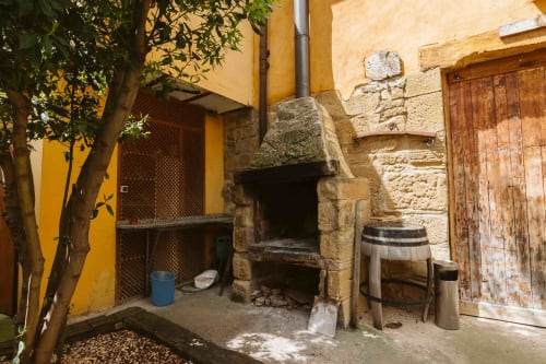 Rustic courtyard at Casas Rurales La Viña with traditional stone fireplace, wooden doors, and green ivy in Cuzcurrita de Río
