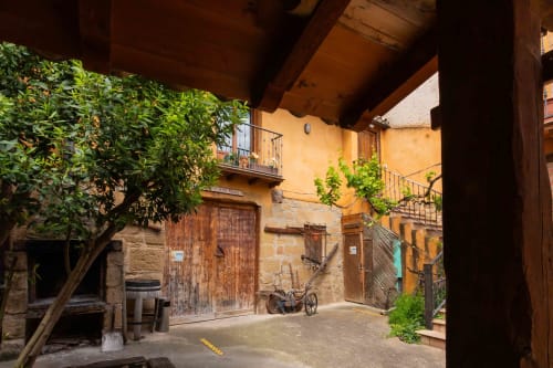 Rustic courtyard at Casas Rurales La Viña in Cuzcurrita de Río Tirón with stone buildings, wooden doors, and ivy-covered