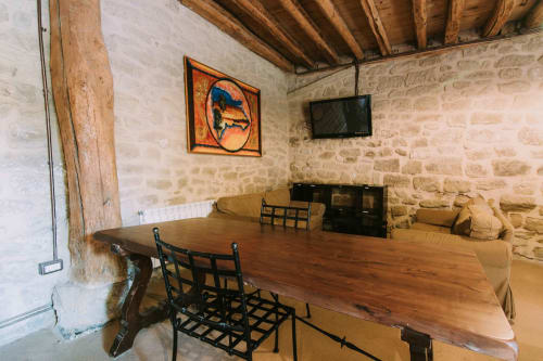 Rustic stone apartment interior at La Viña with wooden dining table, black chairs, exposed beams, and TV at Casas Rurales