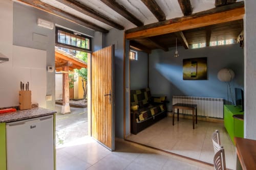 Modern open-plan kitchen and living room at Casas Rurales La Viña with exposed beams, terrace access, and comfortable seating