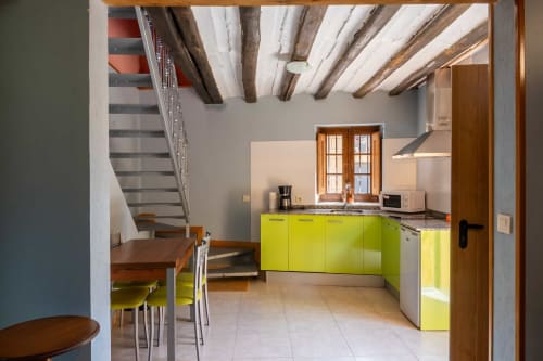Modern kitchen with bright yellow cabinets, exposed wooden beams, and dining area at Casas Rurales La Viña, Cuzcurrita de Río