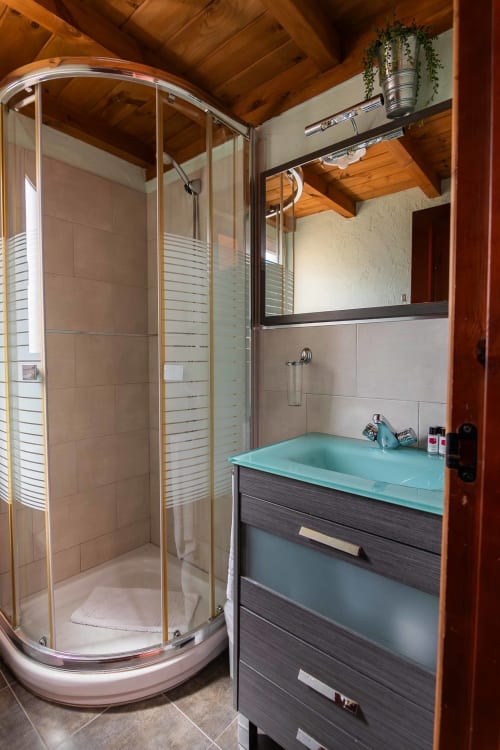 Modern bathroom with turquoise sink, dark wood vanity, and curved glass shower enclosure in La Viña 3 room at Casas Rurales