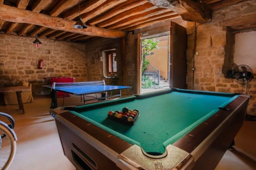Rustic game room at Casas Rurales La Viña with pool table, ping pong, exposed wooden beams and stone walls