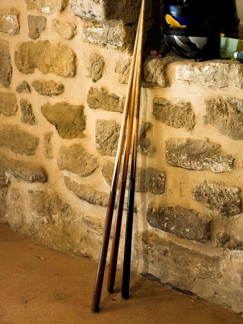 Fishing rods leaning against rustic stone wall in La Viña 3 room at Casas Rurales La Viña, Cuzcurrita de Río Tirón