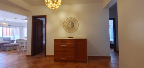 Amplia sala de estar en apartamento Casa Juana, El Médano, con muebles de madera, espejo decorativo e iluminación moderna