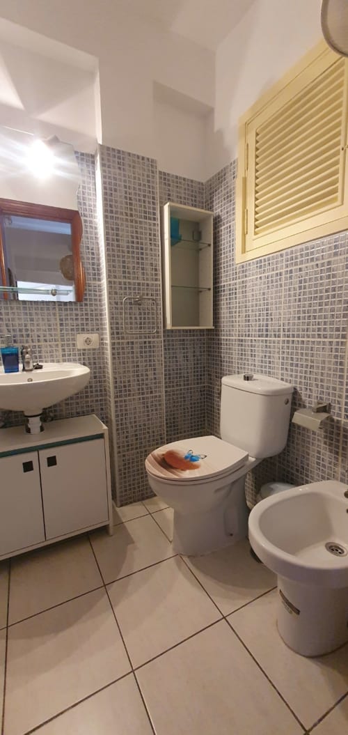 Baño moderno en Casa Juana, apartamento El Médano con paredes alicatadas, inodoro, lavabo y armario amarillo