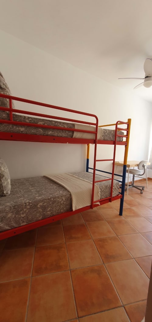 Cama litera de metal rojo con colchones estampados en dormitorio luminoso de Casa Juana, El Médano