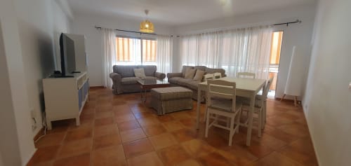 Amplia sala de estar en apartamento Casa Juana, El Médano, con suelos de terracota, zona de descanso, mesa de comedor y balcón