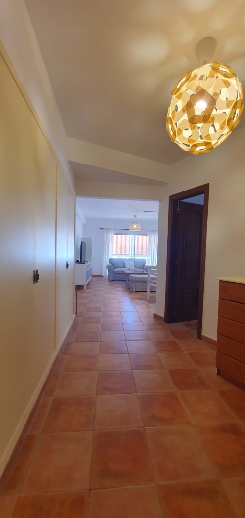 Pasillo moderno del apartamento Casa Juana en Alquila en Canarias, El Médano, con baldosas de barro y lámpara dorada en el techo