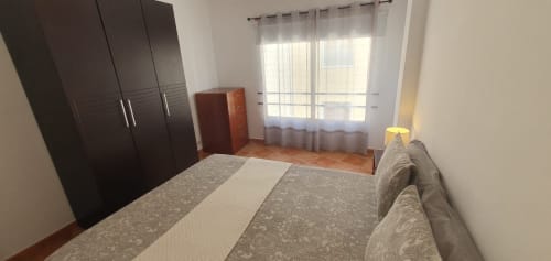 Amplio dormitorio en apartamento Casa Juana, El Médano, con cama, armario oscuro, puertas al balcón y suelo de madera