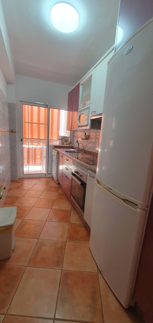 Cocina moderna del apartamento Casa Juana, El Médano Canarias, con electrodomésticos de acero inoxidable y suelos de baldosa terracota