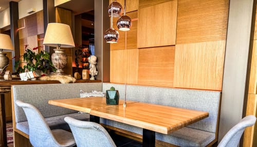 Moderna sala da pranzo dell'Hotel Moderno Restaurant a Serina con tavolo in legno, banquette imbottita grigia e lampade a sospensione.