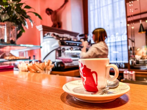 Tazza da caffè rossa al bar del Ristorante Hotel Moderno, Serina. Stazione espresso con barista al lavoro dietro il bancone.