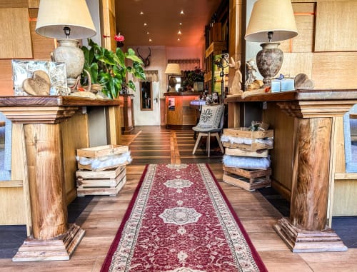 Corridoio d'ingresso del ristorante Hotel Moderno a Serina con colonne in legno, lampade decorative, piante e tappeto runner bordeaux