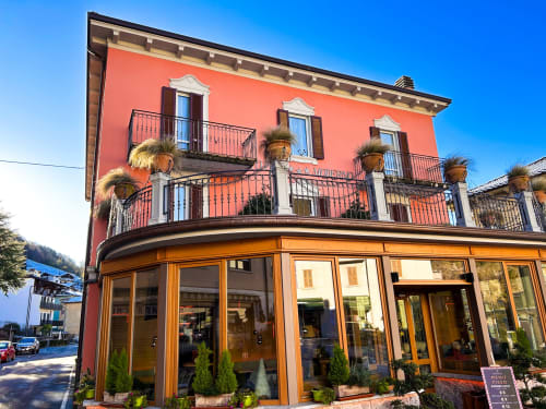 Ristorante Hotel Moderno a Serina, Italia - facciata color corallo con vetrina curva e balconate ornamentali