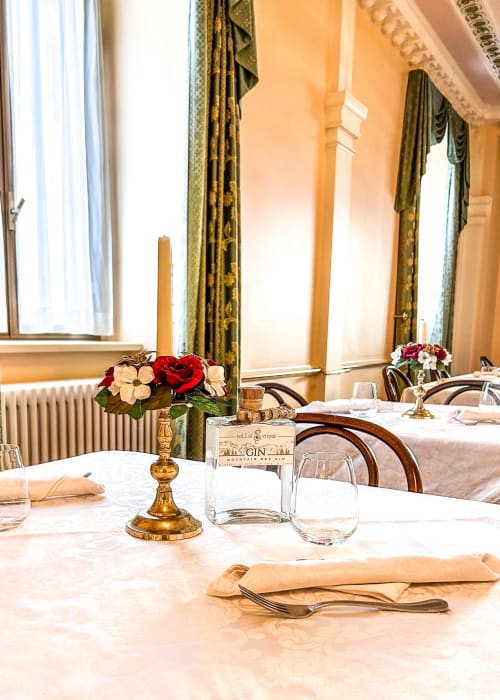 Elegante sala da pranzo del Ristorante Hotel Moderno a Serina con candelabro dorato, composizione floreale e tavoli raffinatamente apparecchiati