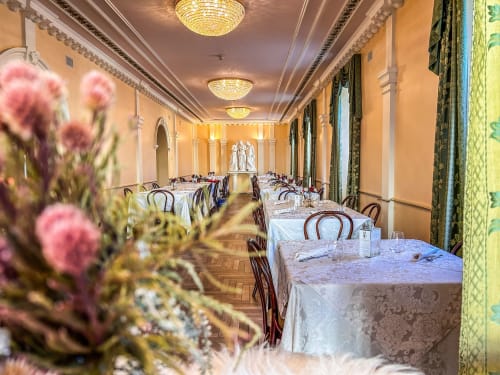 Elegante sala da pranzo del Ristorante Hotel Moderno a Serina con fiori rosa, lampadari e tavoli formalmente apparecchiati