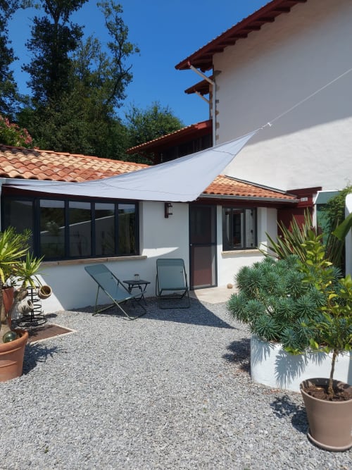 Terrasse de la chambre L'Atelier à Villa Xaran Erdian à Espelette avec voile d'ombrage blanc, transats et vue sur le jardin