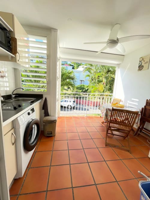 Cuisine et salle à manger modernes chez Kfé Chocolat avec carrelage en terre cuite, électroménagers inox, ventilateur de plafond et jardin tropical