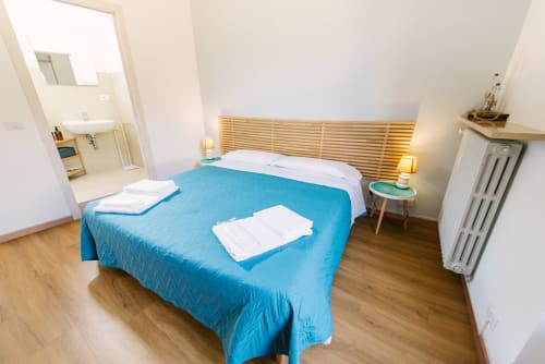 Camera moderna nella guest house di Provincia di Verona con biancheria blu, testata in legno, bagno privato e pavimenti in legno duro