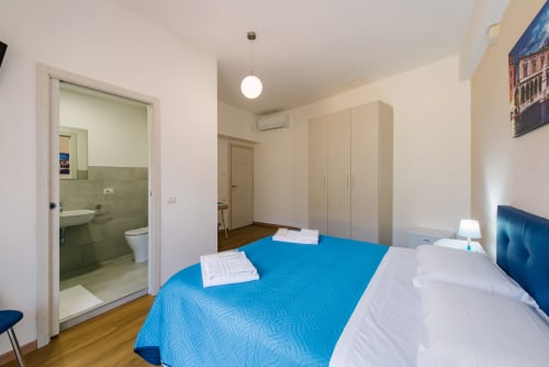 Camera moderna della 3 Guest House a Verona con biancheria blu, bagno en-suite, armadio e pavimento in legno