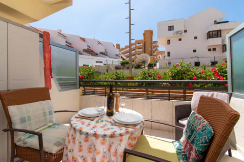 Sunny balcony with dining setup overlooking colorful garden, Costa Adeje apartment