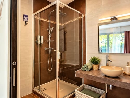 Salle de bain moderne du gîte Cœur d'Hérault avec douche vitrée, vasque ronde et lumière naturelle