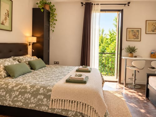 Chambre lumineuse avec lit queen, accents verts et portes-fenêtres donnant sur le jardin à Maison D'hôtes Coeur D'hérault