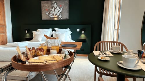 Petit-déjeuner en suite luxe au Palmier Aigues-Mortes avec viennoiseries, pain et café face au lit aux accents verts