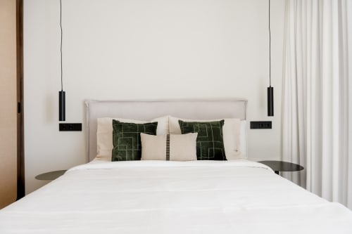 Dormitorio moderno en villa VC Alisio con cama blanca, almohadas verdes estampadas, luces colgantes y vista al mar en Breña Baja