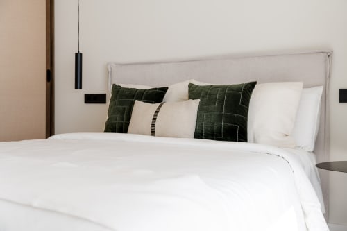 Dormitorio moderno con ropa de cama blanca, almohadas acolchadas verdes e iluminación colgante en la villa VC Luxury Village de Breña Baja