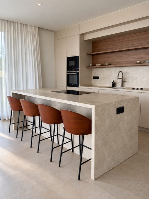 Moderna cocina con gran isla, tres taburetes color óxido y estanterías de madera en villa de VC Luxury Village, Breña Baja