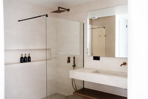 Baño moderno con vanity de piedra blanca, ducha de lluvia, mampara de vidrio y accesorios negros en villa de VC Luxury Village