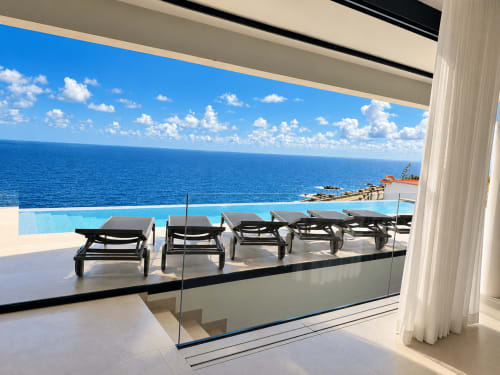 Villa de lujo con terraza, piscina infinita con vista al mar, tumbonas y barandilla de cristal en Breña Baja