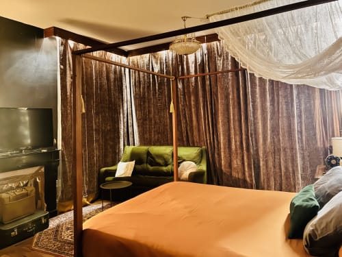 Chambre romantique avec lit à baldaquin, canapé olive, rideaux en velours marron et éclairage chaleureux aux Studios Chez Mary Gannat