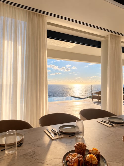 Elegante comedor de la villa V&C Alisio con vistas al mar, piscina infinita y horizonte oceánico al atardecer en Breña Baja.