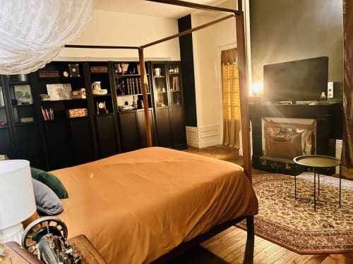 Chambre luxueuse aux Studios Chez Mary Gannat avec lit à baldaquin, étagères noires, TV et cheminée