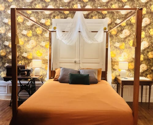 Lit à quatre colonnes avec literie orange et voilages blancs à baldaquin aux Studios Chez Mary Gannat, papier peint à motifs floraux