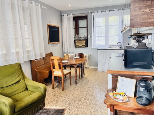 Espace de vie ouvert avec fauteuil vert, table à manger, kitchenette et fenêtres chez Chez Mary Studios à Gannat