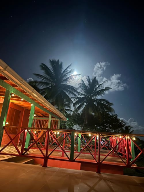 Terraza de cabaña Seaflower Boutique Lodge de noche con barandales rojos, palmeras y luz de luna en San Andrés