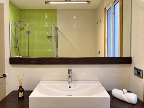 Baño moderno en apartamento Aire de Baiona, Baiona con pared de ducha verde lima, lavamanos blanco, estante de madera oscura y diseño contemporáneo