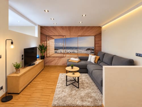 Luminosa sala de estar del apartamento Aire de Baiona en Baiona, con sofá gris, muebles de madera y vistas al océano