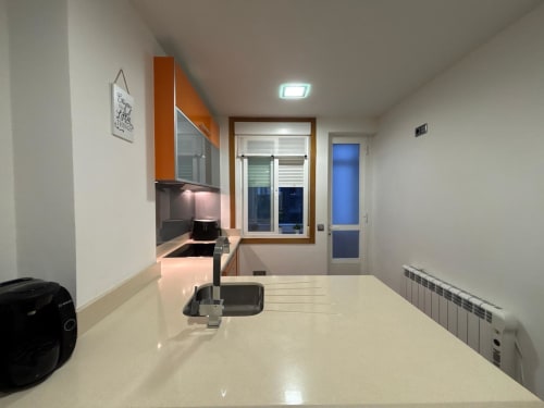 Cocina y comedor modernos en el apartamento Aire de Baiona con encimera blanca y puertas con vistas a la ciudad