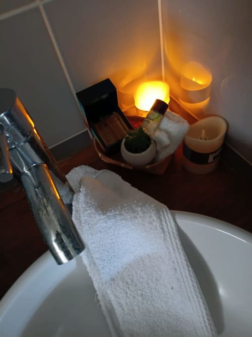 Bathroom vanity at Le Nid De Bellemont cottage with lit candles, toiletries, and folded white towels in Trois-Rivières