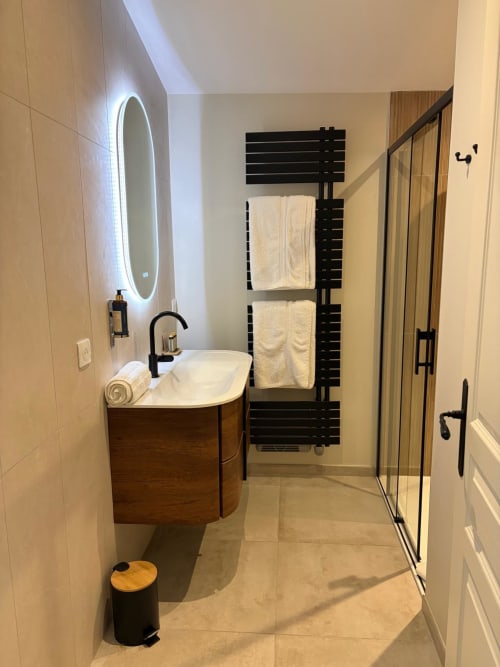 Salle de bain moderne à la Chambre Le Chai du Château Alto Cormeil, Saint-Émilion, avec meuble vasque en bois, porte-serviettes noir et