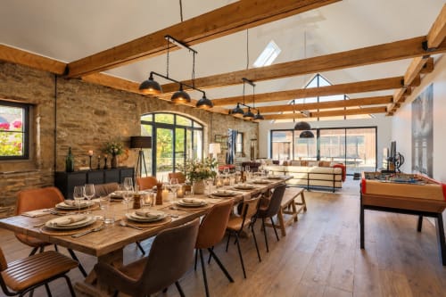 Salle à manger spacieuse dans la villa de Plestin-les-Grèves avec poutres en bois, table dressée et baby-foot